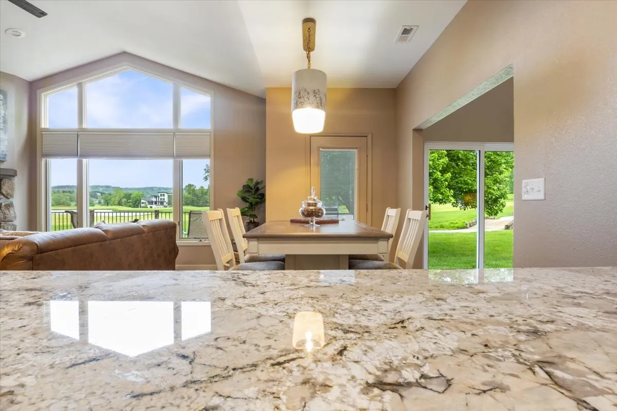 A warm and welcoming dining area with a granite countertop, a dining table, and large windows offering a scenic outdoor view. The space is filled with natural light, inviting guests to gather, dine, and enjoy the surroundings.