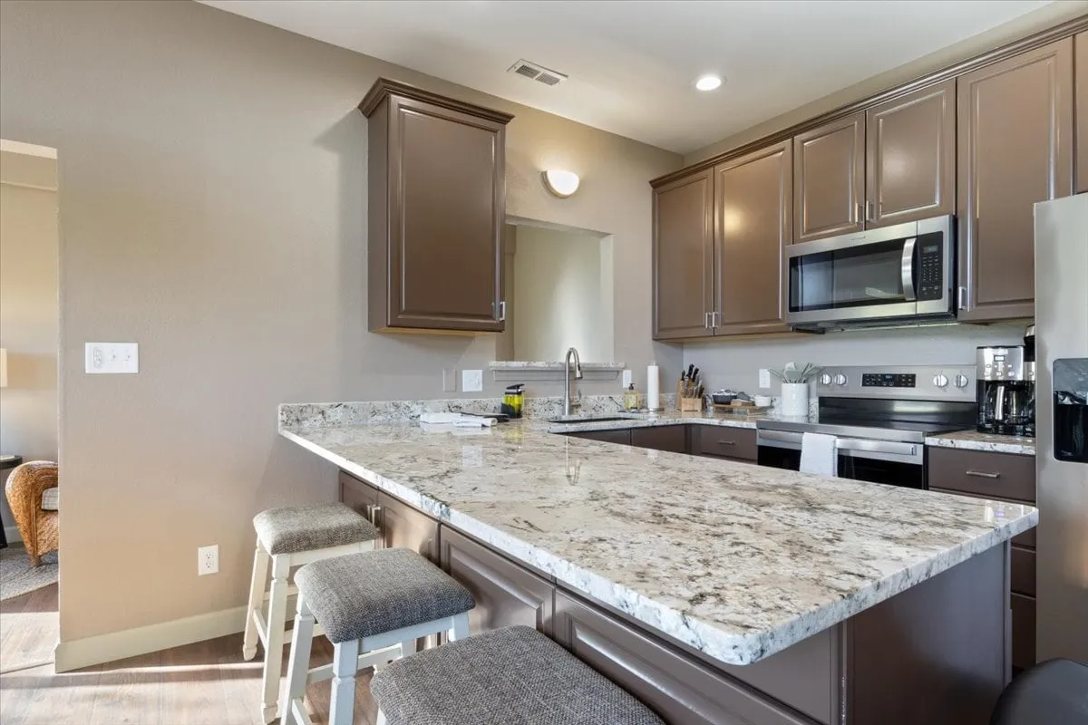 A modern kitchen with granite countertops, stainless steel appliances, and a central kitchen island, designed for both cooking and socializing. The space is well-lit and exudes a warm, welcoming vibe, making it suitable for meal prep, brunches, or festive occasions.