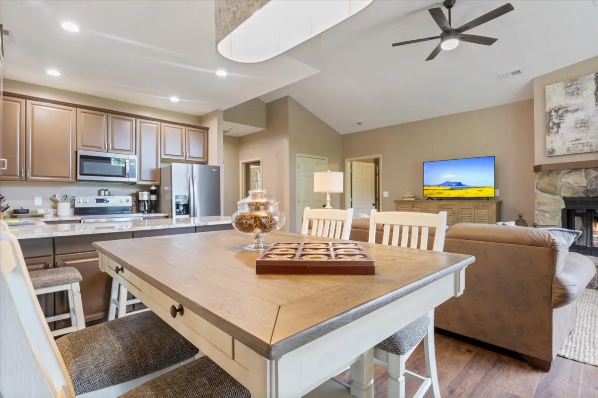 An open-concept space that seamlessly brings together the dining table, kitchen island, sofa, and television, creating an inviting environment ideal for socializing, family meals, cooking, and relaxing. The kitchen and dining zones are visually connected, reflecting the flow described in the section.