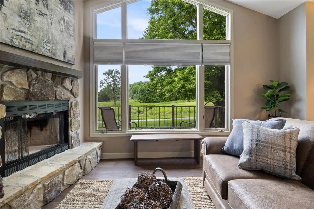 A serene living area featuring a plush sofa, fireplace, large windows, and a coffee table. The windows offer a glimpse of the outdoors, making it an inviting spot for both socializing and enjoying views of the resort grounds.