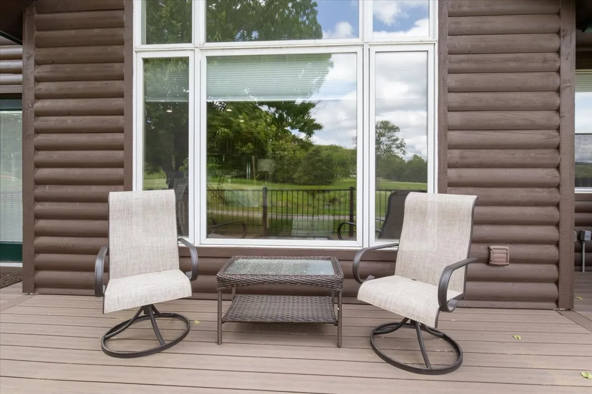Two classic rocking chairs and a small coffee table are set on a porch with large windows overlooking lush natural scenery. The calm, tranquil mood conveys peaceful mornings and evenings spent enjoying the outdoors—ideal for multigenerational gatherings or quiet family moments.