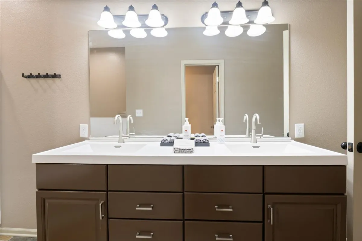 A bright, modern bathroom with a double sink vanity, a large mirror, and stylish light fixtures. The atmosphere is fresh and inviting, suggesting ease of morning routines and spaciousness for guests.