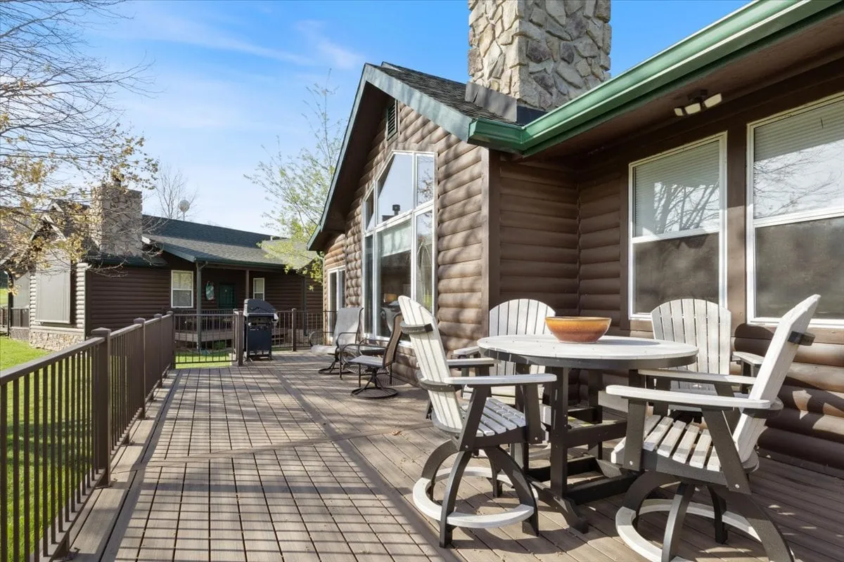This image features an outdoor dining set on a natural wood deck, with a stone chimney in view. The surrounding scenery suggests a peaceful, nature-oriented setting, perfect for enjoying meals outdoors while overlooking the golf course or lush fairways.